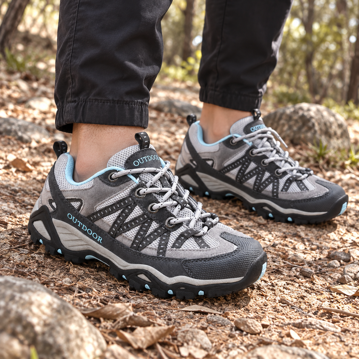Paire de chaussures randonnée mailles grises portée sur un sentier sec