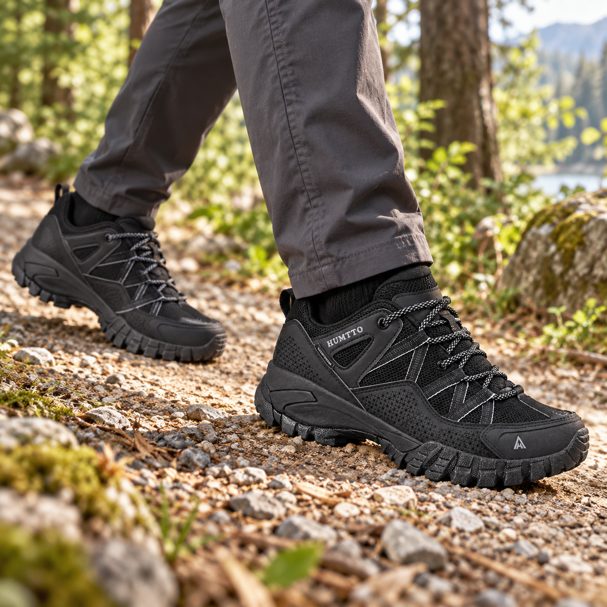 Deux chaussures randonnée noires basses portées sur sentier de gravier