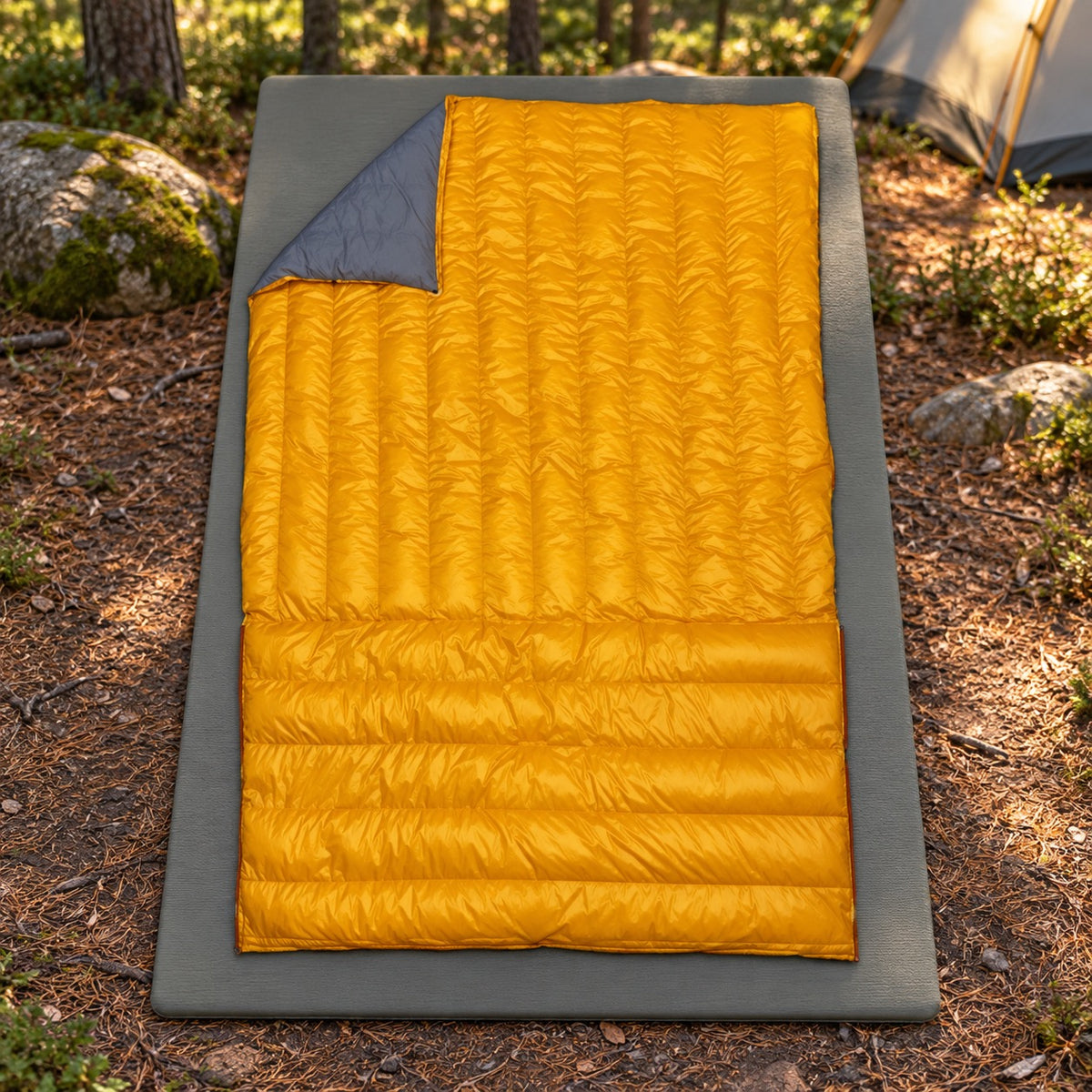 Sac de couchage rectangulaire homme jaune déployé sur tapis au camping
